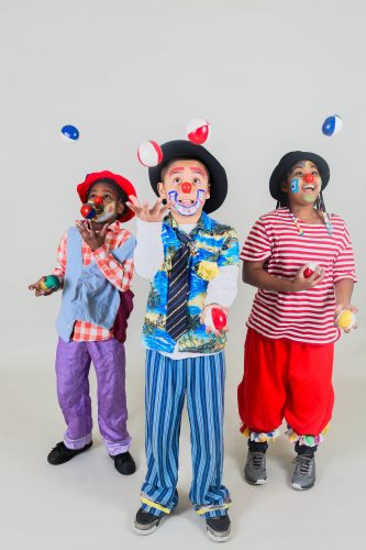 three children in clown make up juggling bean bags